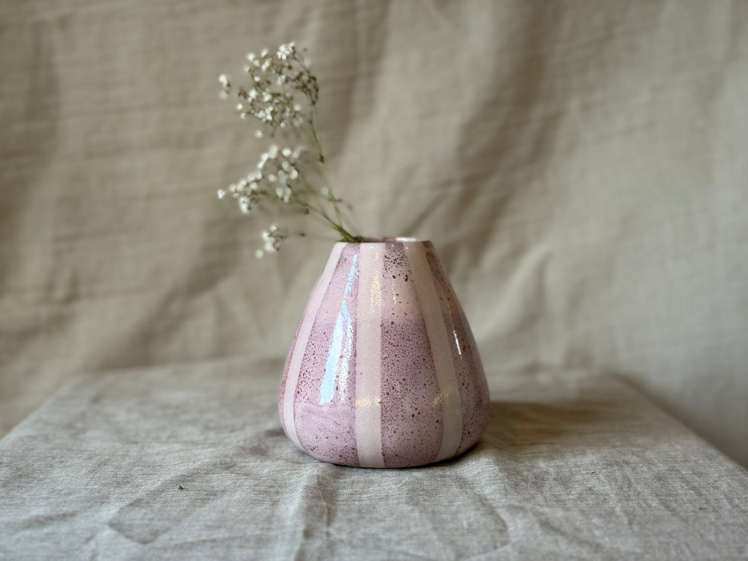 pink stripey pear shaped vase with a dried flower stem